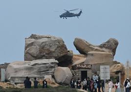 Un helicóptero militar chino sobrevuela a los turistas en un mirador sobre el Estrecho de Taiwán, en la isla de Pingtan