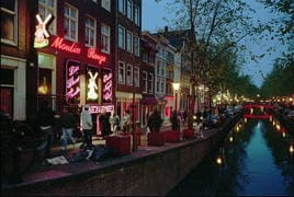 Varias personas pasan frente a los burdeles de una de las calles del Barrio Rojo en Ámsterdam