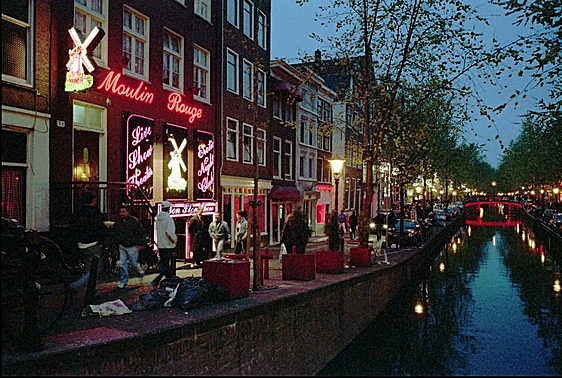 Varias personas pasan frente a los burdeles de una de las calles del Barrio Rojo en Ámsterdam