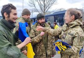 Una militar reparte banderas de Ucrania a los soldados liberados en el intercambio de prisioneros.