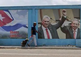 Un hombre camina frente a un fotografía del presidente de la República de Cuba Miguel Díaz-Canel junto a su predecesor, Raúl Castro, en La Habana.