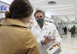 Un empleado de una farmacia atiende a una clienta.