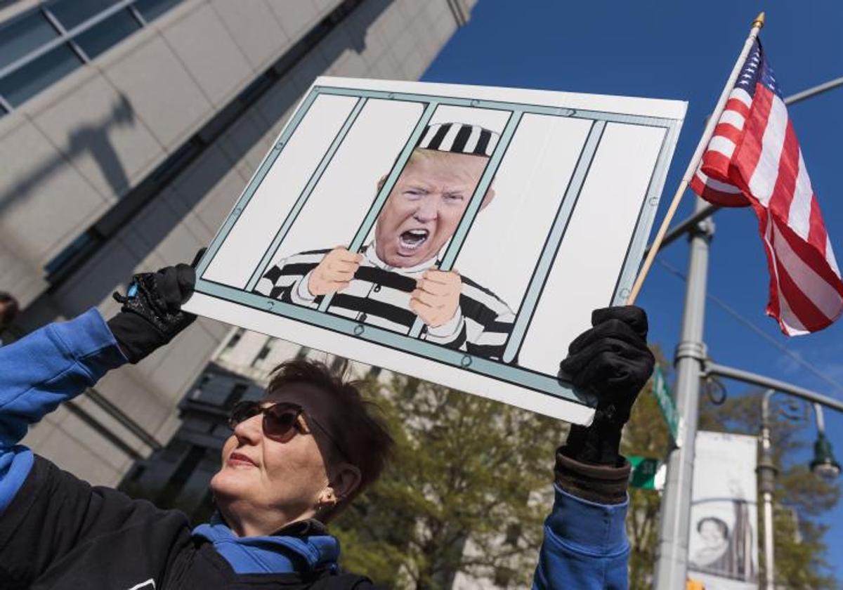 Una mujer protesta contra Tump, al comienzo del juicio.