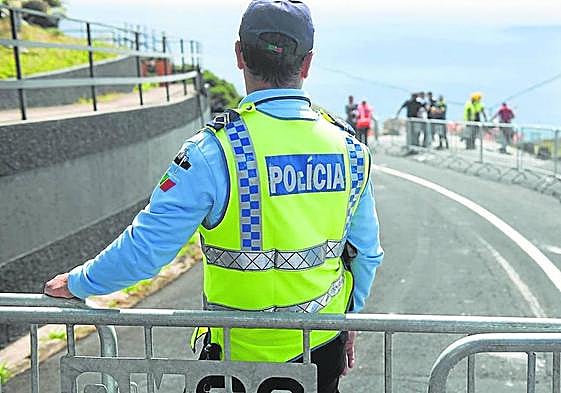 Un policía portugués hace guardia tras una valla que cierra el paso a los curiosos.