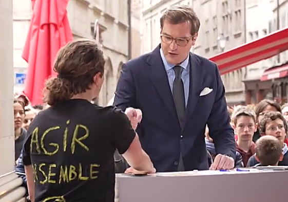 Un ecologista pega su mano al atril de un periodista durante un debate político en Ginebra