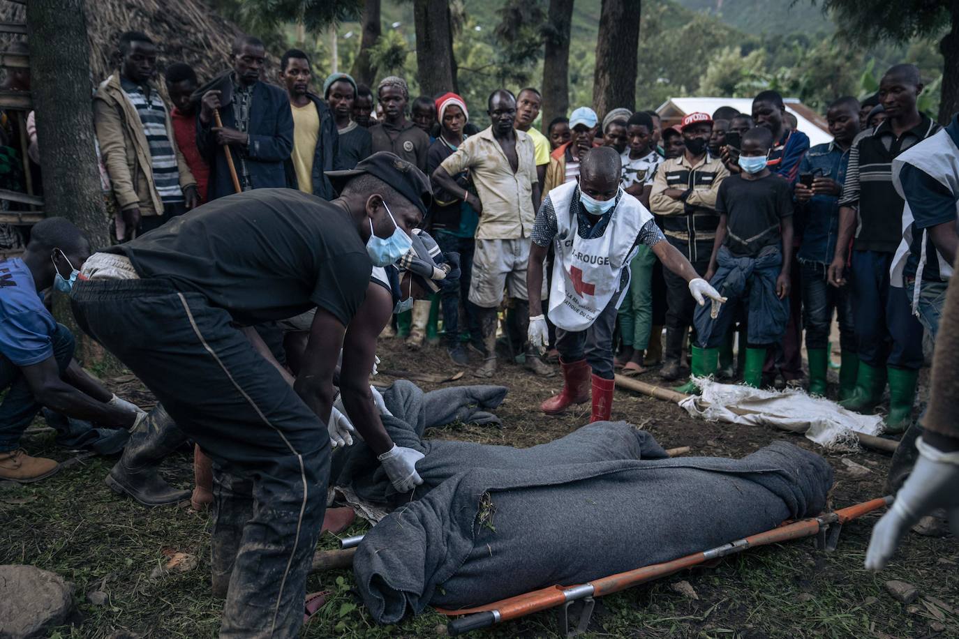 Un voluntario de la Cruz Roja y vecinos de Nyamukubi envuelven en mantas los cuerpos de las personas que murieron en las fuertes inundaciones