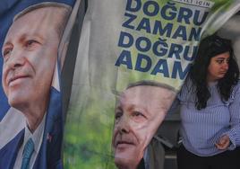 Una mujer junto a carteles de campaña que muestran al presidente turco, Recep Tayyip Erdogan.