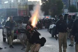 Un policía dispara al aire para dispersar a manifestantes en Karachi.