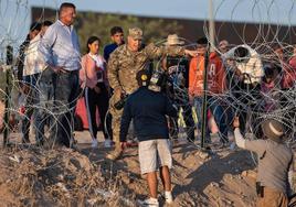 Un militar norteamericano frena el intento de dos migrantes de cruzar un paso fronterizo entre México y EE UU