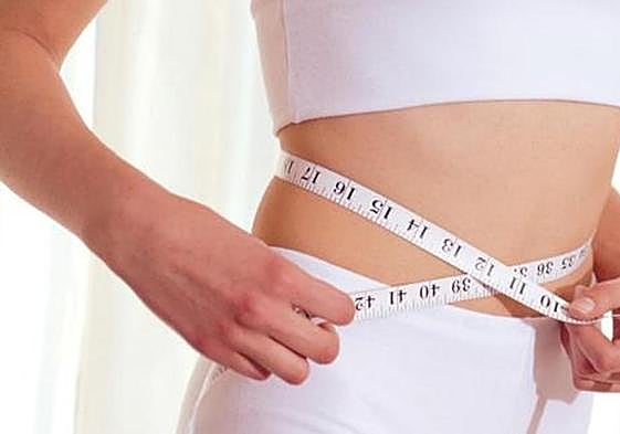 Una mujer se mide la cintura.