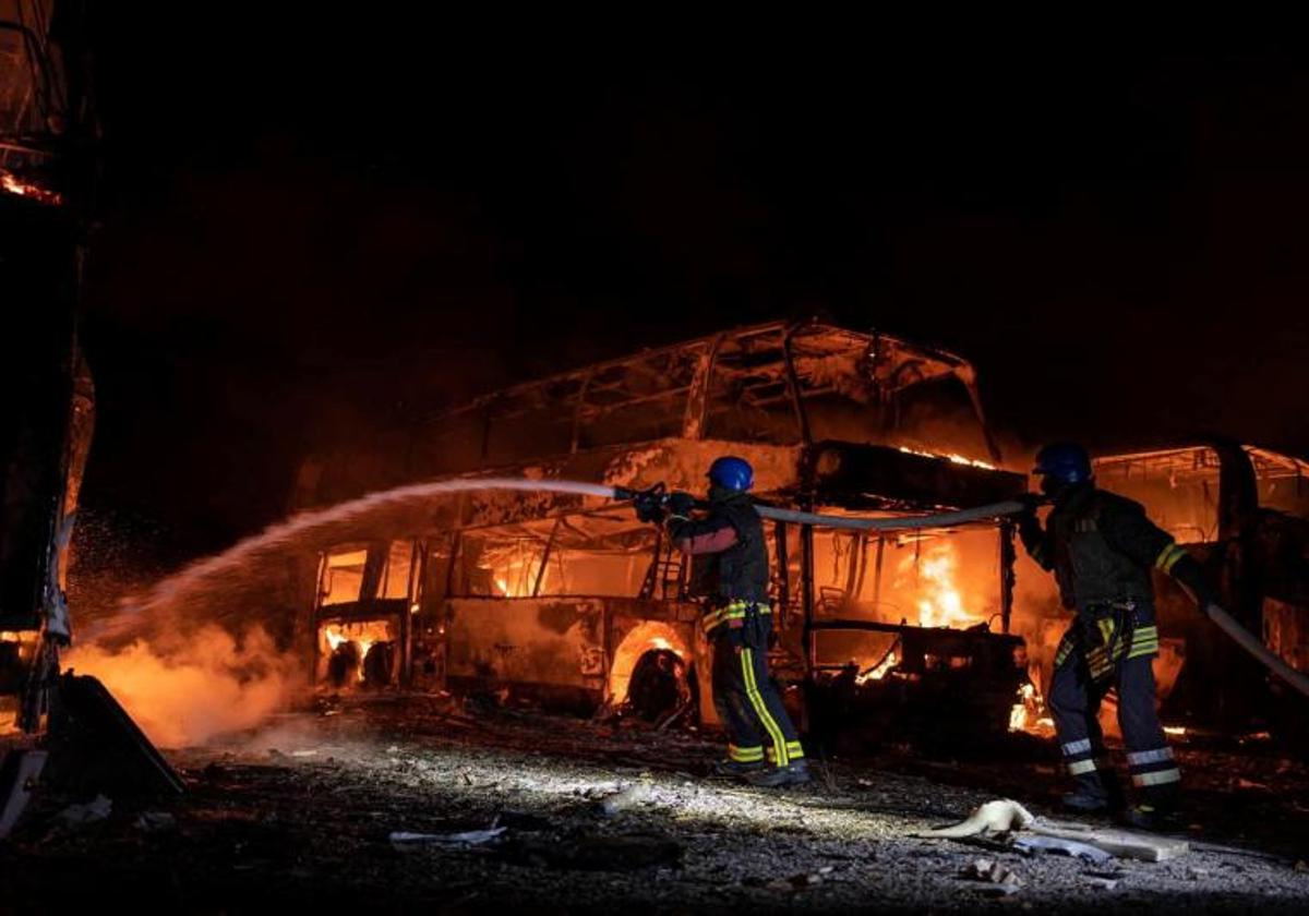 Los bomberos de Kiev trabajan para sofocar un autobús incendiado tras ser alcanzado por un misil ruso.