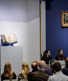 Imagen secundaria 2 - En la imagen superior, detalle de una de las páginas del 'Codex Sassoon'; debajo, uno de los empleados de Sotheby's muestra la biblia a los posibles compradores; por último, una vista de la sala de subastas en Nueva York durante la puja.