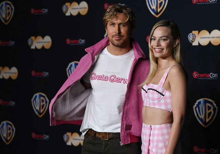 Ryan Gosling junto Margot Robbie vistiendo una película con el nombre de Greta Gerwig
