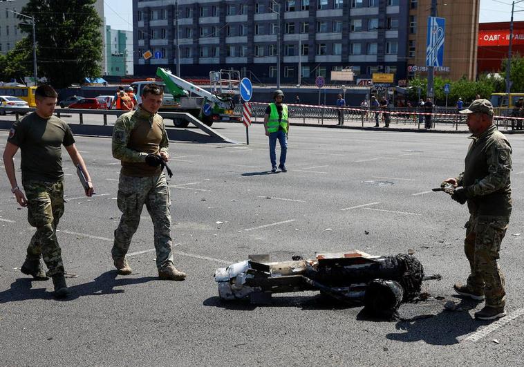 Tres agentes de policía caminan junto a la parte de un misil que ha aterrizado en una calle de Kiev durante un ataque ruso