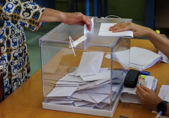 Una mujer introduce su voto en una urna.