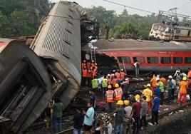 Viajeros intentan escapar de uno de los trenes volcados en el estado indio de Odisha tras el choque.