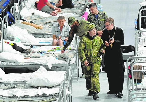 Un sacerdote visita el centro de acogida de urgencia habilitado en el polideportivo de Bélgorod.