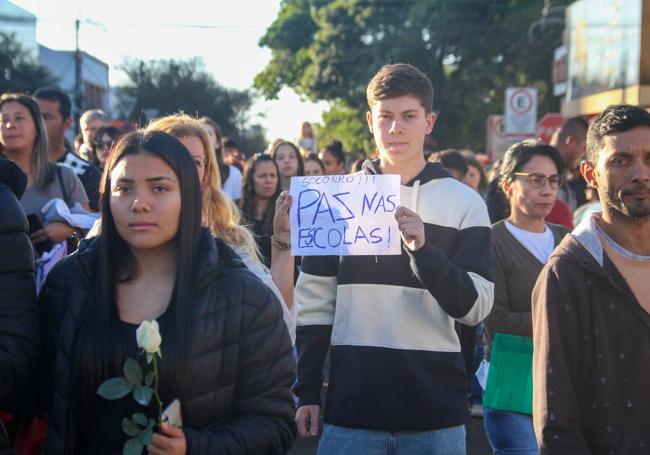 Varias personas caminan con el mensaje «Paz en las escuelas» durante el enterriero de dos jovenes asesinados en un centro educativo de Brasil