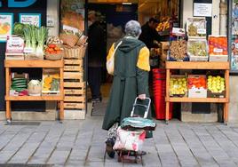 Una mujer frente a una frutería.