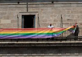 Dos funcionarios colocan la bandera arcoíris en uno de los balcones del Palau de la Generalitat Valenciana para conmemorar los actos del Orgullo.
