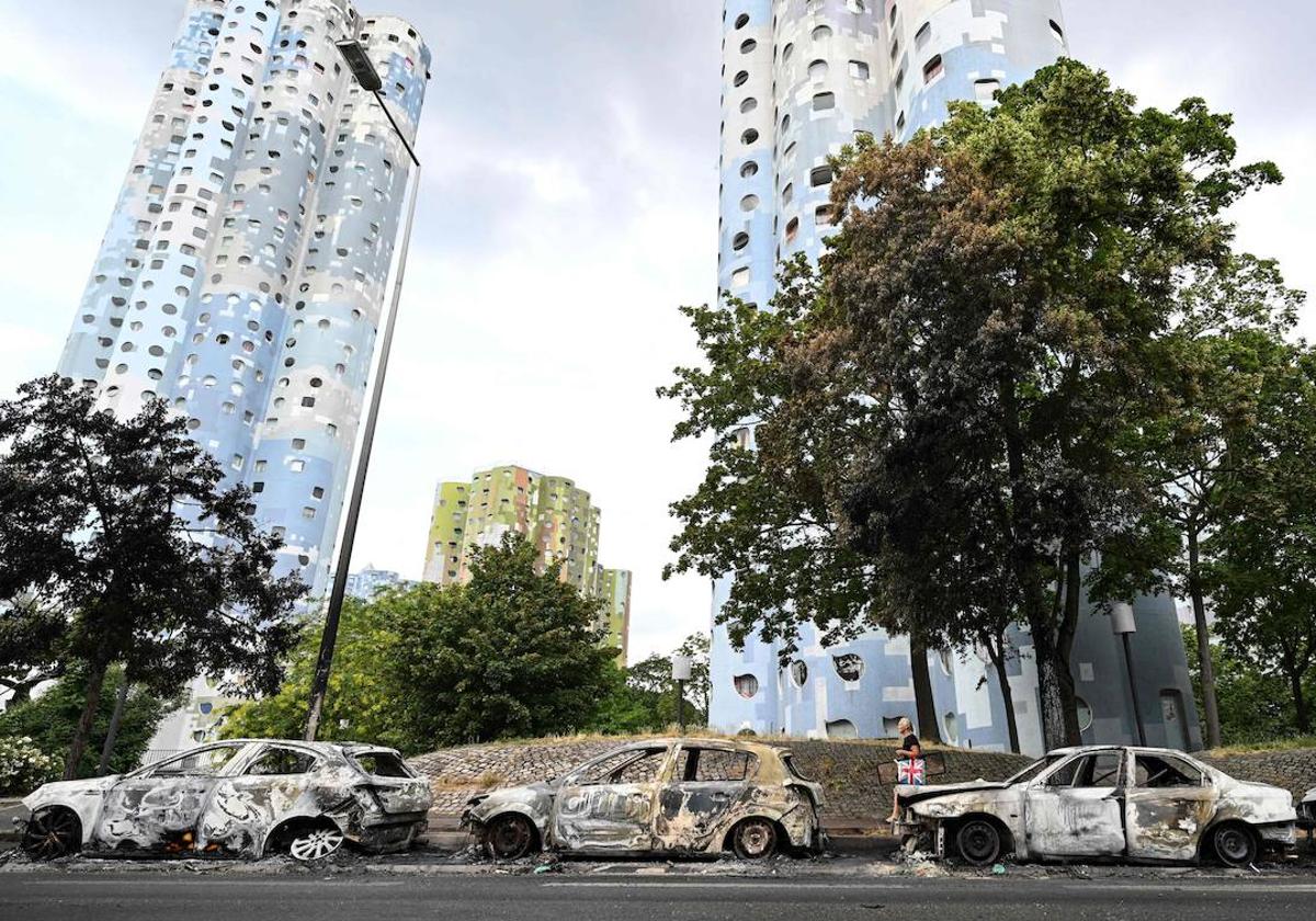 Una hilera de coches calcinados a los pies de las típicas construcciones, en forma de colmena, de los suburbios franceses, en este caso en Nanterre.