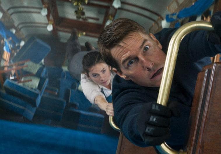 Tom Cruise y Hayley Atwell, como Ethan y Grace, aferrados a un tren que se desploma.