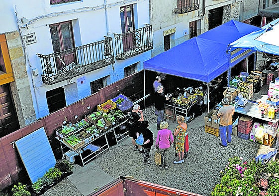 Plaza Mayor de Budia, en Guadalajara, donde vecinos y veraneantes hacen cola en un puesto ambulante de frutas.