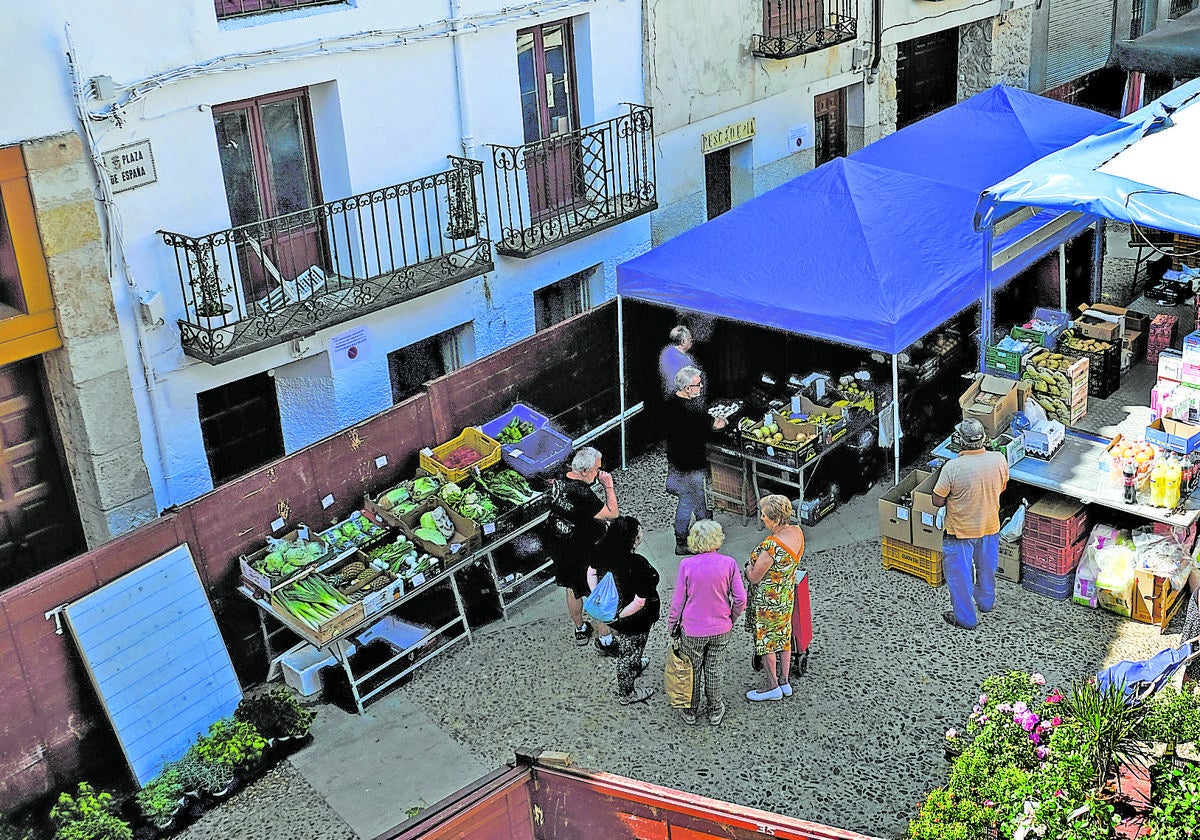 Plaza Mayor de Budia, en Guadalajara, donde vecinos y veraneantes hacen cola en un puesto ambulante de frutas.