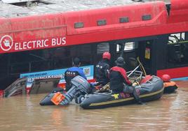 Los buzos examinan el autobús atrapado por las aguas en busca de supervivientes.