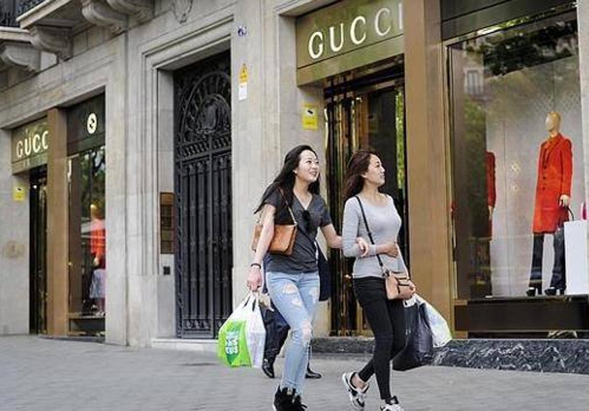 Dos turistas chinas pasean delante de una tienda de Gucci.