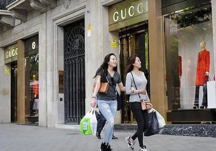Dos turistas chinas pasean delante de una tienda de Gucci.