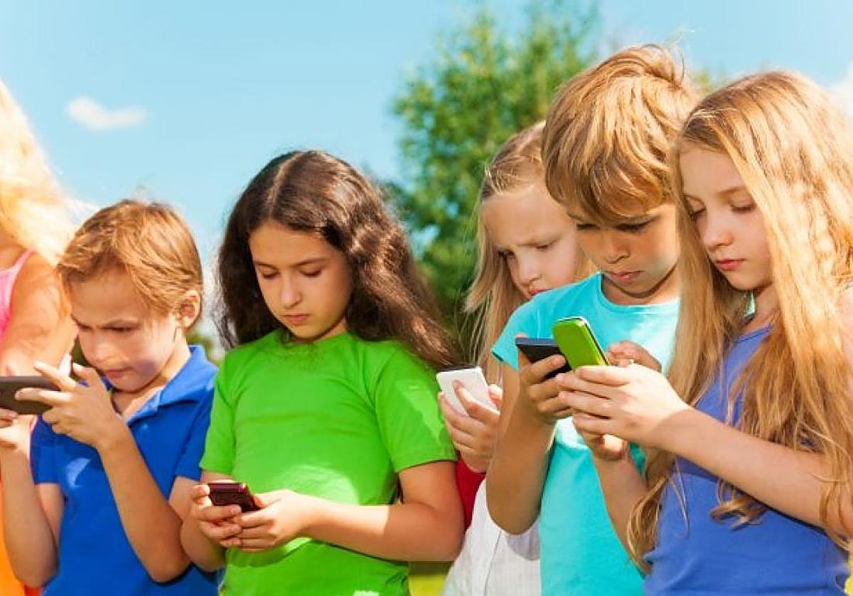 Varios menores mirando móviles.