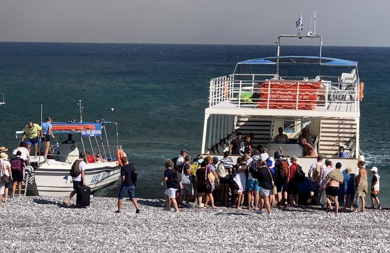 Un grupo de turistas es evacuado por mar desde una playa.