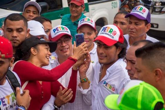 Una simpatizante se hace una foto del presidente Petro y su hijo, Nicolás, en una campaña electoral.