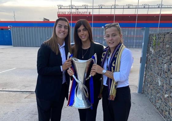 Carlota Planas (centro), junto a Patri Guijarro a la izquierda y Claudia Pina a la derecha, posa con el trofeo de la Champions femenina lograda por el Barcelona.