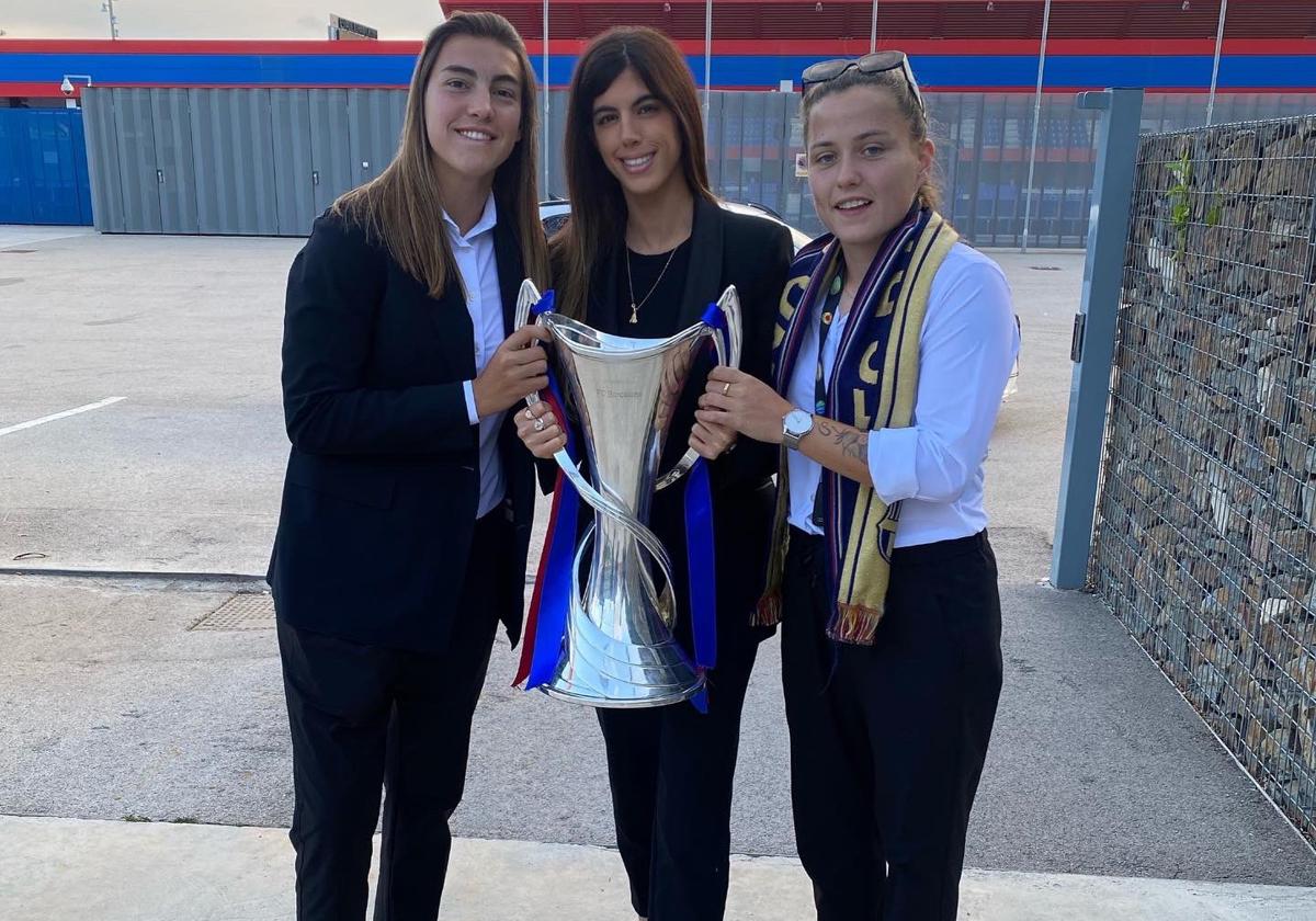 Carlota Planas (centro), junto a Patri Guijarro a la izquierda y Claudia Pina a la derecha, posa con el trofeo de la Champions femenina lograda por el Barcelona.