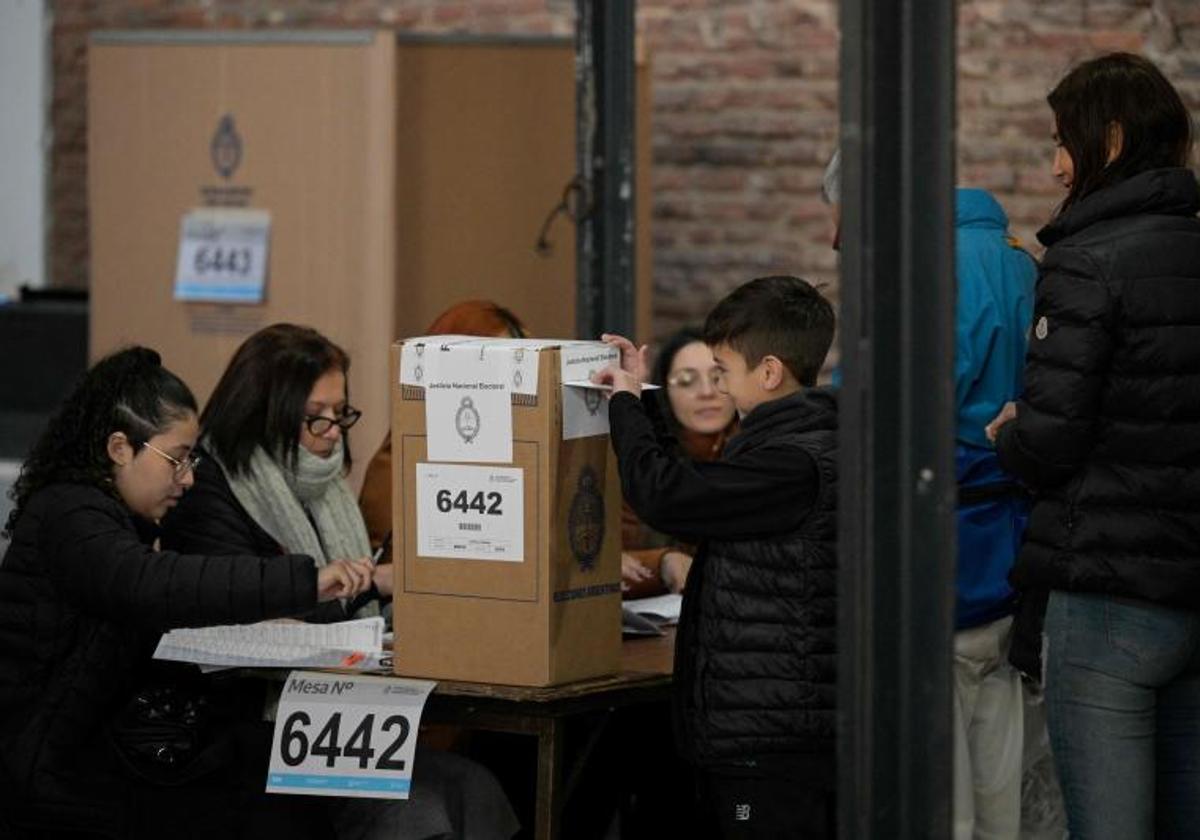 Un niño ayuda a su madre a votar en un colegio de Buenos Aires durante las elecciones primarias celebradas ayer en Argentina.