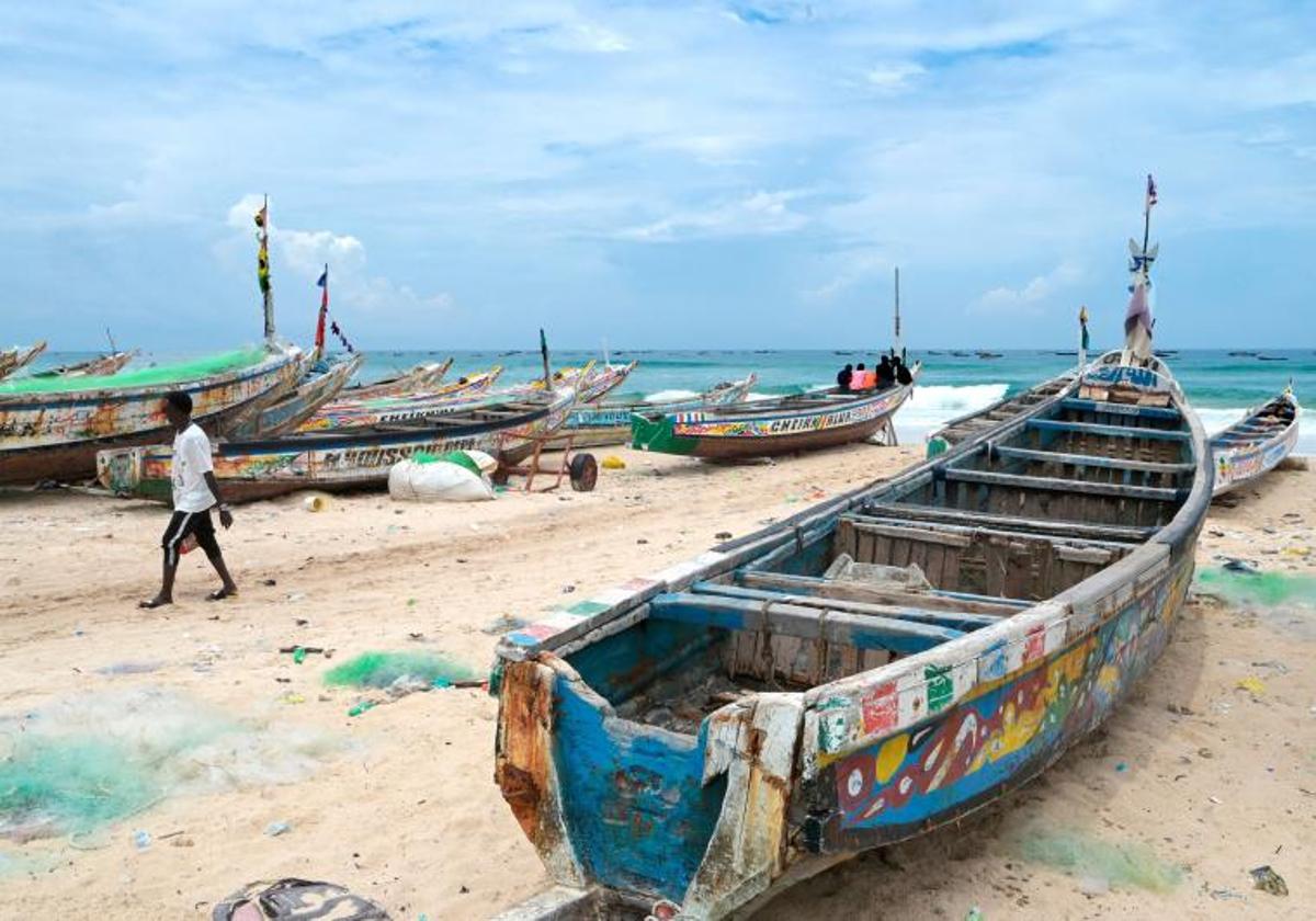 Un hombre pasea entre varias barcas en Fass Boye, de donde partió el cayuco senegalés que quedó a la deriva.