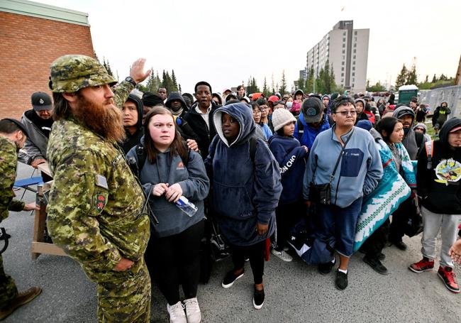 La gente hace fila afuera de una escuela local para registrarse para ser evacuada de Yellowknife