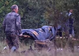 Dos miembros de los equipos de emergencias transportan una bolsa para cadáveres cerca de los restos del avión privado vinculado al jefe de los mercenarios de Wagner, Evgeny Prigozhin