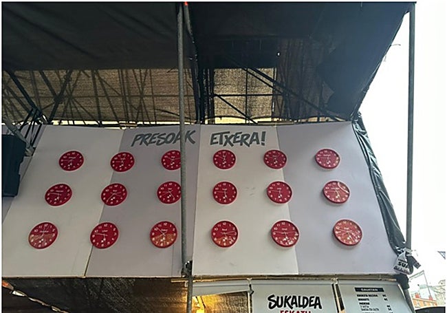 El motivo de la caseta es un gran reloj de cuco del que sale un pájaro carpintero y en cuyo frontal están colocados de manera dispersa relojes con fotografías familiares de los presos homenajeados DIGNIDAD Y JUSTICIA