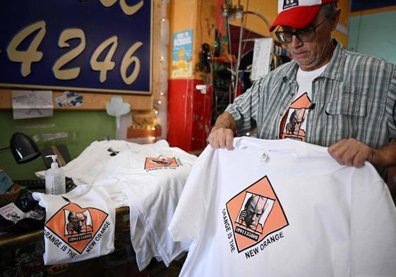 El propietario de una tienda dobla camisetas con fotografías policiales de Trump