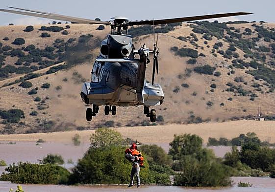 Un helicóptero y su tripulación trabajan para rescatar a una persona varadas en una zona inundada