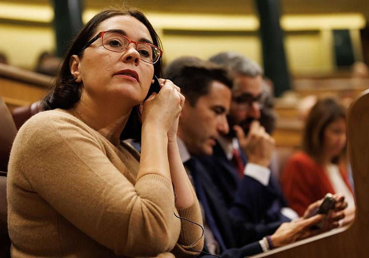 Una diputada se pone el pinganillo durante una sesión plenaria, en el Congreso de los Diputados