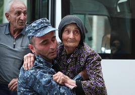 Un agente de policía armenio ayuda a una refugiada de la región de Nagorno Karabaj