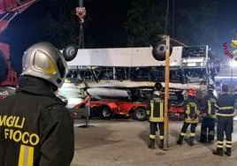 Bomberos retiran los restos del autobús que cayó de un puente y se incendió en la localidad italiana de Mestre.