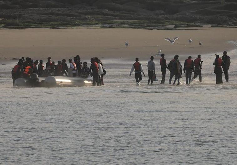 Un grupo de migrantes desembarca en la playa francesa de Le Portel después de un intento fallido de cruzar el Canal de la Mancha.