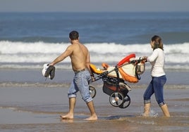 Una pareja pasea con su hijo por la orilla durante sus vacaciones de verano.