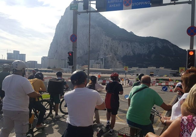 Trabajadores españoles esperan en la frontera el aterrizaje de un avión en el aeropuerto de Gibraltar para poder pasar a la colonia británica.