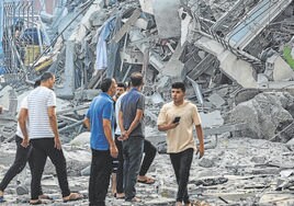 Un grupo de gazatíes observa los escombros de un edificio destruido por la aviación israelí.